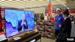 Люди в окупованому Криму дивляться у магазині пресконференцію Путіна. 17 грудня 2020 року