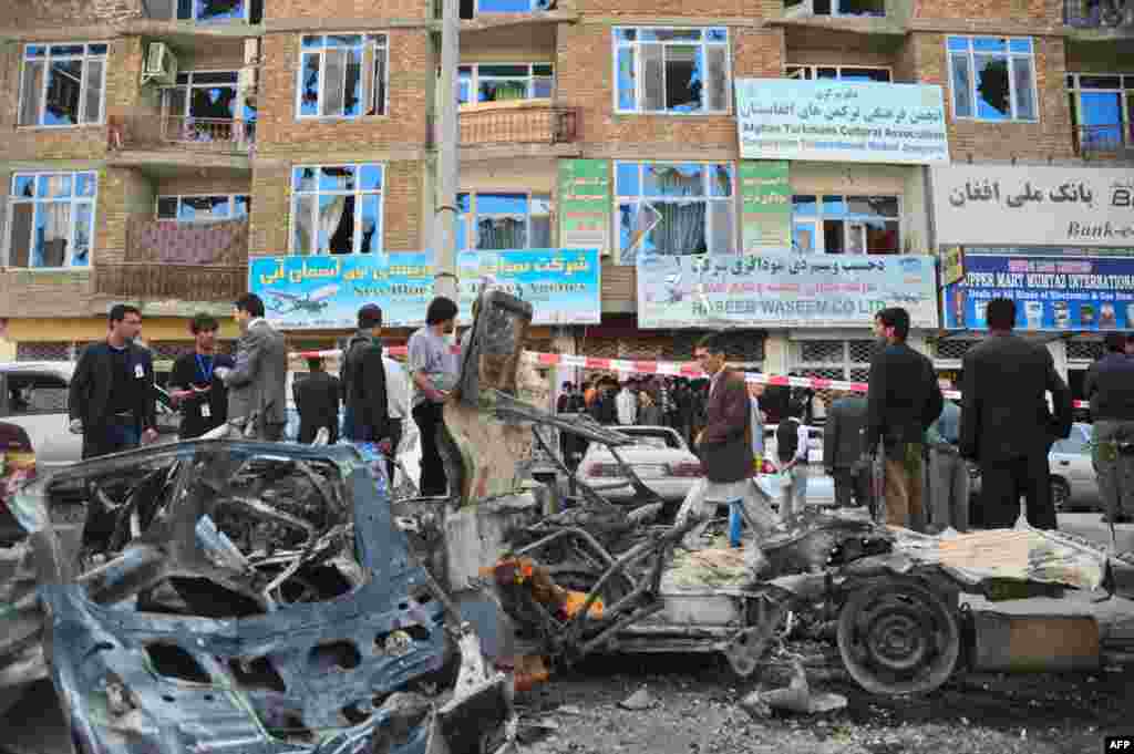 Security personnel on April 16 cordon off the wreckage of cars in front of a building at the site of one of the attacks in Kabul. (AFP)