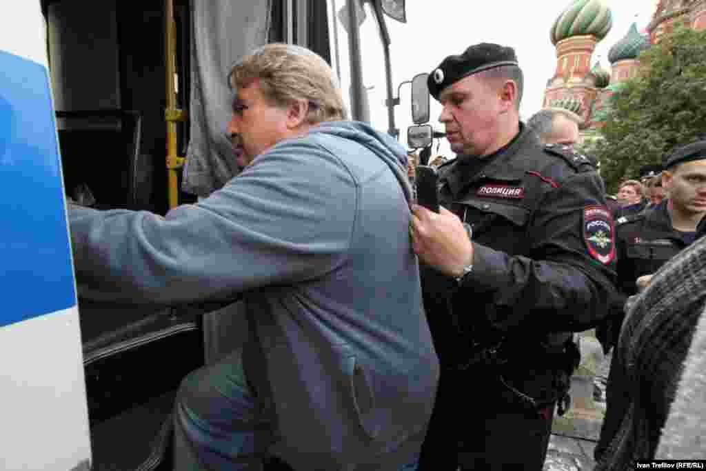 Задержанного активиста Рыклина заводят в полицейский автобус.