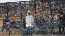 Putnici na stanici javnog prevoza na fizičkoj distanci zbog korona virusa u sred snega u Skoplju 1. aprila