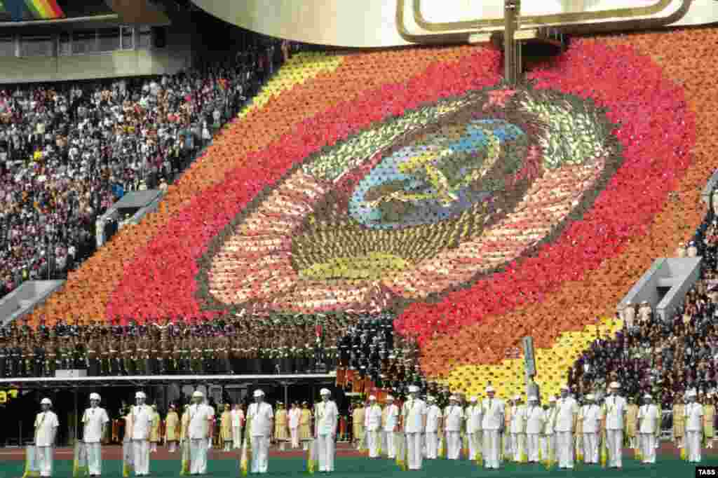 Hundreds of participants create a giant hammer and sickle emblem in the stands. 
