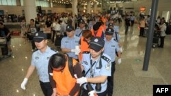 Őket nem Kambodzsában fogták el, de hasonlóban utaztak: kínai rendőrök vezetnek el a pekingi reptéren tizenhárom kínai állampolgárt, akit Srí Lankán fogtak el egy 11,5 millió dolláros online csalásban való részvételért. Peking, 2012. május 30.