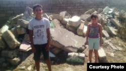 Mağazanın söküntüsündən sonra sahibkarın uşaqları daş-qalaqların qarşısında.