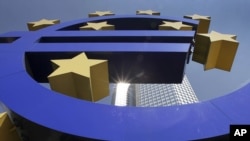 Germany -- The sun is reflected on the facade of the European Central Bank ECB Tower, seen through the Euro symbol, in Frankfurt, 06Aug2009