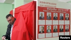 A man leaves a voting booth with posters of the presidential candidates at a polling station in Minsk on December 19.