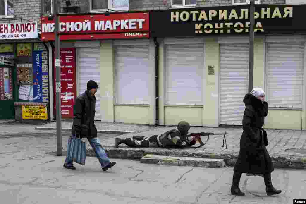 A pro-Russian rebel takes cover during what Ukrainian separatists said was an antiterrorist drill in Donetsk on March 18. (Reuters/​Marko Djurica)