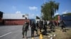 Security personnel prepare for deployment beside shipping containers placed by authorities blocking the Islamabad-Rawalpindi highway to stop protesters from entering the capital for an anti-France rally.