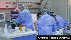 Doi asistenți îi pun masca de oxigen unui pacient din secția ATI de la Institutul Marius Nasta.