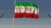 Flamuri i Iranit që valëvitet prapa telat me gjemba. Fotografi ilustruese.