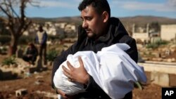 Un bărbat poartă cadavrul unui membru al familiei într-un cimitir din orașul Jinderis, provincia Alep, Siria, marți, 7 februarie 2023