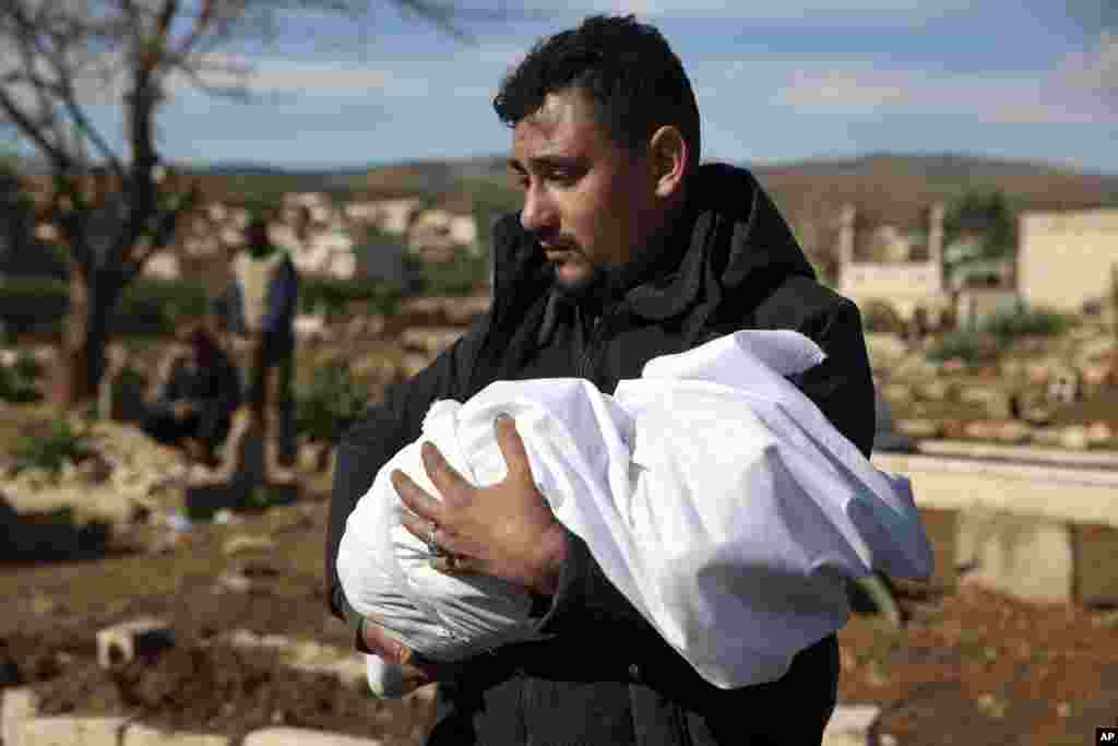 Un bărbat duce în brațe cadavrul unui membru al familiei care a murit într-un cutremur devastator care a zguduit Siria și Turcia într-un cimitir din orașul Jinderis, provincia Alep, Siria, marți, 7 februarie 2023.
