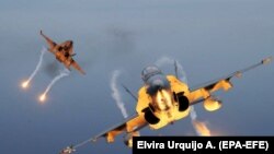 Două avioane de vânătoare F-18 lansează rachete de semnalizare în timp ce participă la exercițiile militare Ocean Sky ale statelor membre NATO, Statele Unite ale Americii, Turcia și Spania, în Baza Forțelor Aeriene Gando, în Gando, Insulele Canare, 25 octombrie 2019