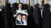 A woman holds a portrait of former and current supreme leaders, Ayatollah Ruhollah Khomeini and Ayatollah Ali Khamenei, as she queues up to vote on February 21 at the Shah Abdul Azim shrine on the southern outskirts of Tehran.