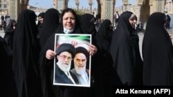 A woman holds a portrait of former and current supreme leaders, Ayatollah Ruhollah Khomeini and Ayatollah Ali Khamenei, as she queues up to vote on February 21 at the Shah Abdul Azim shrine on the southern outskirts of Tehran.