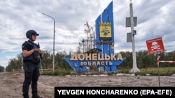 Genist ucrainean la intrarea în oblastul Donețk, pe granița simbolică între zonele Harkov și Donețk și lângă un semn pe care scrie „Pericol de mine", Ucraina, 20 septembrie 2022