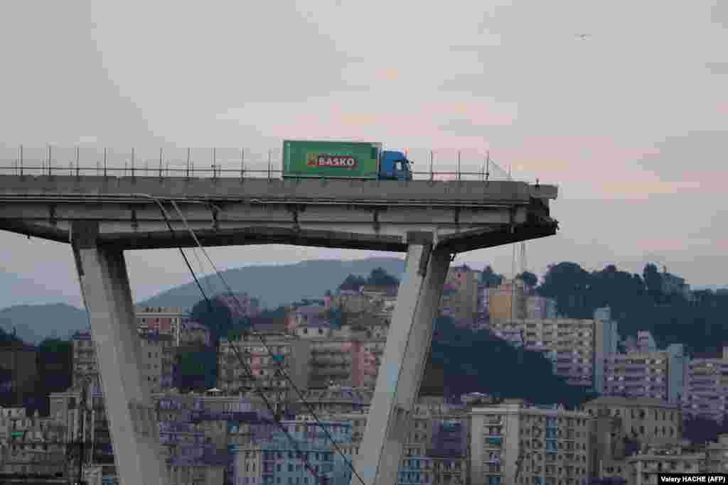 A truck stands on the edge of the collapsed Morandi motorway bridge in the northwestern Italian city of Genoa on August 14. Forty-three people were killed when the bridge collapsed during torrential rainfall. The collapse, which saw a vast stretch of the freeway tumble onto railway lines, came as the bridge was undergoing maintenance work. (AFP/Valery Hache)