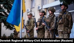 Ukrainian military personnel take part in a ceremony to raise the Ukrainian flag over Lyman after its liberation on October 4.