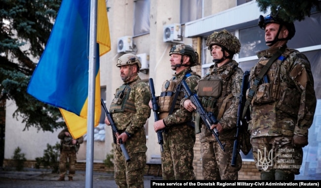 Ukrainian military personnel take part in a ceremony to raise the Ukrainian flag over Lyman after its liberation on October 4.