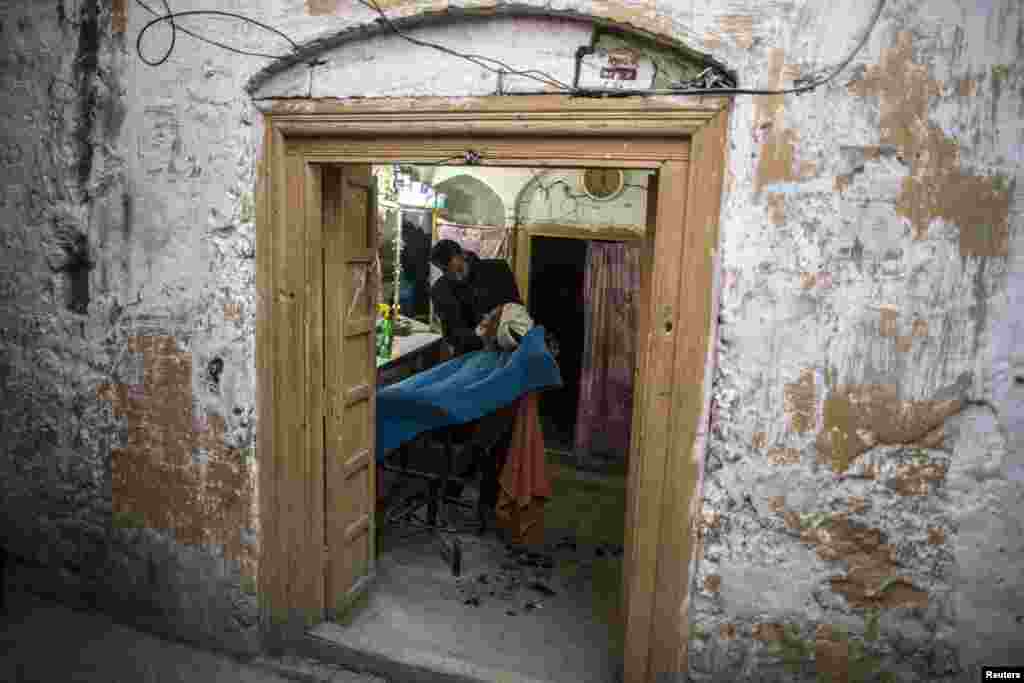 A barber shaves a customer at his shop in Islamabad. (Reuters/​Zohra Bensemra)