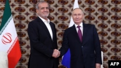 Președintele rus Vladimir Putin (dreapta) dă mâna cu președintele iranian Masud Pezeshkian la Așgabat pe 11 octombrie.