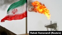 A gas flare on an oil production platform in the Soroush oil fields is seen alongside an Iranian flag in the Gulf 