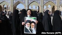 An Iranian woman holds a portrait of former and current Supreme Leaders, Ayatollah Ruhollah Khomeini and Ayatollah Ali Khamenei, at the polling statation at the Shah Abdul Azim shrine in the south of Tehran, February 21, 2020. 