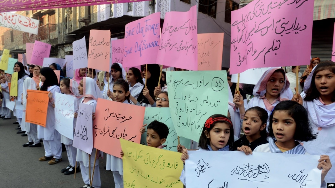 Pakistani students of Farooqi Girls' High School wave placards as they stage a protest in Lahore on November 3, demanding the reopening of their school after it was set on fire by an angry mob.