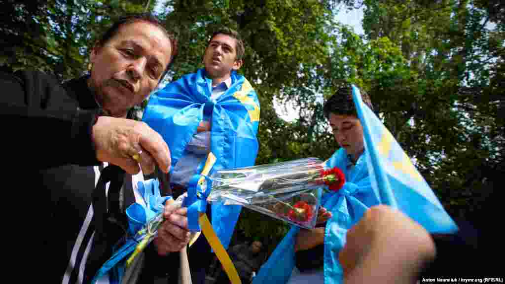 Люди держат в руках крымско-татарские флаги.