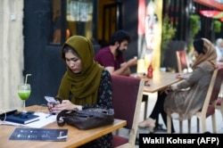 An Afghan woman uses her mobile phone in a cafe in Kabul in early August, before the fall of the country to the Taliban.