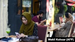 Një grua afgane përdor telefonin e saj celular në një kafene në Kabul në fillim të gushtit, para rënies së vendit në duart e talibanëve.