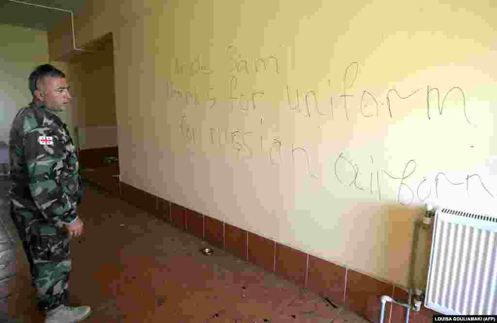 A Georgian soldier looks at a message left by Russian troops inside a base in Senaki after the 2008 Russo-Georgian war. The base was trashed by Russian troops who destroyed tanks and helicopters before withdrawing.