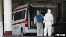 Armenia -- Workers disinfect an ambulance outside Surp Girgor Lusavorich hospital in Yerevan, April 8, 2020.