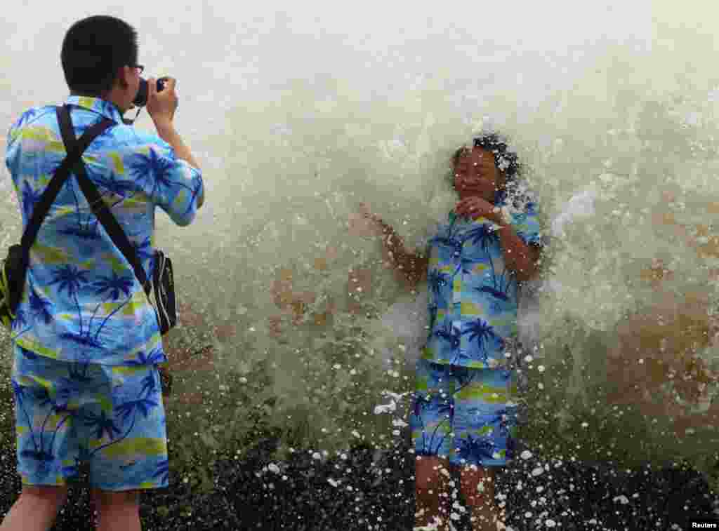 Tourists take pictures as a storm surge hits the coastline under the influence of Typoon Wutip in Sanya in China's Hainan Province. (Reuters)