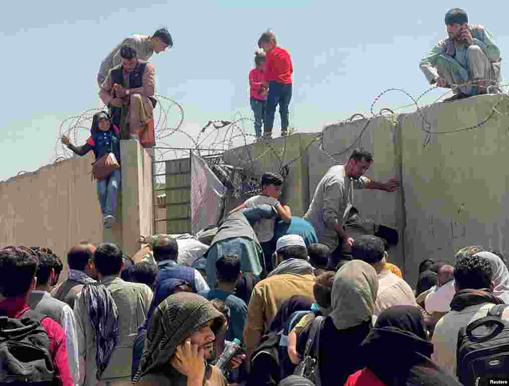 A man pulls a girl over the wall of the airport.&nbsp;