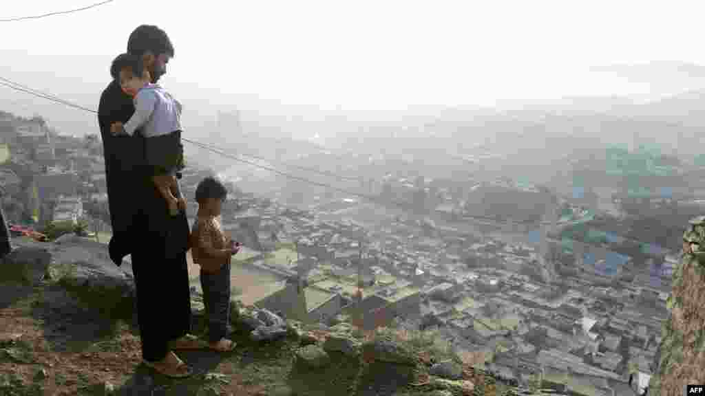 Ahmad Tazim, who makes a living as a construction worker, stands with his two sons Naim (right), 5, and Karim, 2, in front of his home in the hillside neighborhood of Jamal Mina high above Kabul, Afghanistan, on September 27. (AFP/Roberto Schmidt)