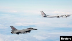 A Norwegian F-16 jet fighter (left) tracks a Russian Tupolev Tu-95 strategic bomber earlier this year. In 2014, there was a marked increase in the number of times NATO aircraft intercepted Russian planes probing alliance defenses.