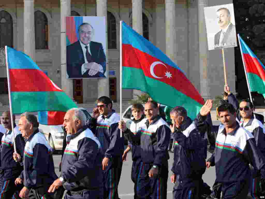 epa01519144 Azeri men hold national flags and posters of candidate and present President of Azerbaijan Ilkham Aliyev take part in a a rally supporting his candidacy in the upcoming presidential elections in Sumgait, some 30km from Baku, Azerbaijan, 13 October 2008. Seeped in oil wealth and in the cross hairs of a regional power struggle between the US and Russia, Azerbaijan votes on 15 October to reelect President Ilham Aliyev, whose only real opponents will be boycotting the polls. Aliyev, 46, replaced his strongarm father Heydar Aliyev in 2003. Obeservers say there is as good as no chance the coming election will break the 35 years of dynastic rule over the Caspian state.