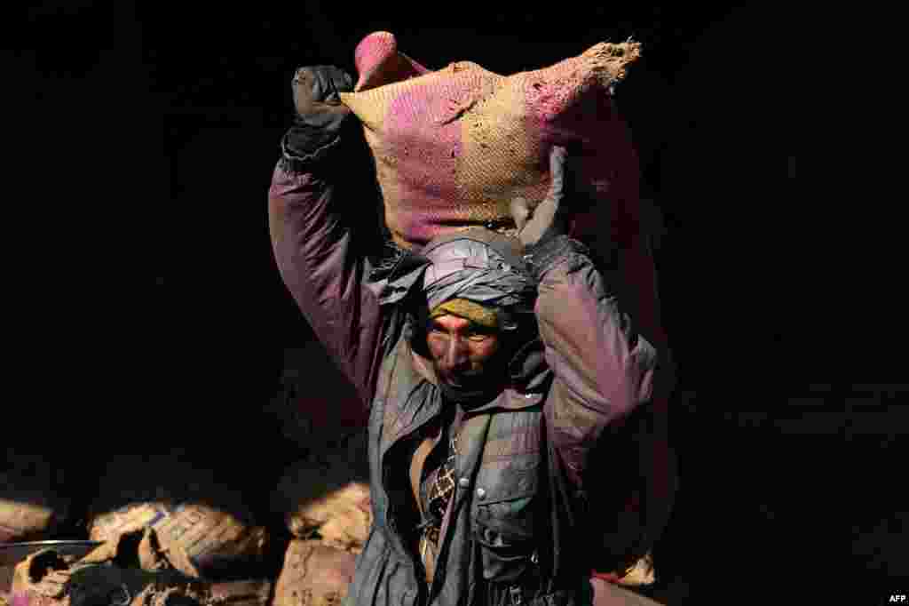 An Afghan laborer carries a sack of coal over his shoulder at a coal yard in Herat. (AFP/Aref Karimi)