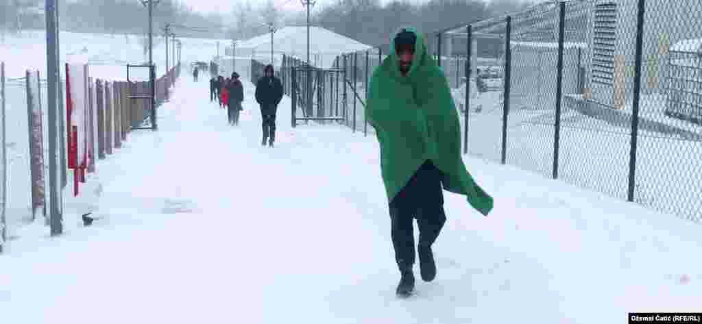 Migrants walk through the snow at the Lipa camp.&nbsp;Some live in squats in the woods around Bihac.