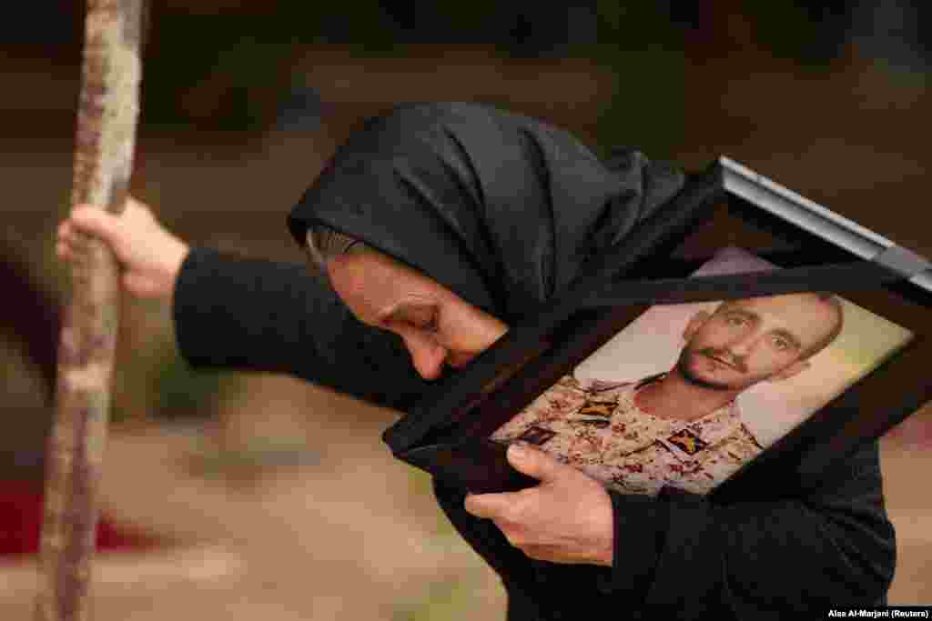 A woman in a Tehran cemetery on March 16 holds a portrait of her son who was reportedly killed by a US-Israeli strike. 
