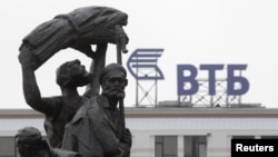 Russia -- Part of a monument to Soviet state founder Vladimir Lenin is seen against a sign for VTB Bank in Stavropol, January 22, 2015