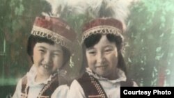Childhood photo of filmmaker Janyl Jusupjan (left) with her sister Salima wearing traditional Kyrgyz clothing made by their mother.