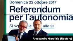 Ілюстрацыйнае фота. Лідэр партыі Forza Italia Сільвіё Бэрлюсконі паказвае сыстэму для галасаваньня разам з прэзыдэнтам Лямбардыі Рабэрта Мароні падчас прэс-канфэрэнцыі аб  рэфэрэндумах у Міляне, 18 кастрычніка 2017 году