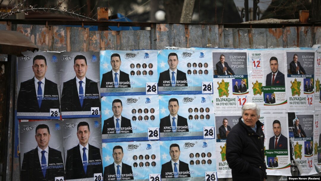 A woman walks past election posters of the ruling center-right GERB party in the town of Dupnitsa, Bulgaria, April 2, 2021.