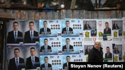 A woman walks past election posters of the ruling center-right GERB party in the town of Dupnitsa, Bulgaria, April 2, 2021.