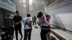 Iran -- People run along a street amid smoke following the Israeli strikes on Iran