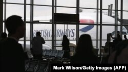 مسافران در حال تماشای یک هواپیمایی بریتیش‌ارویز هنگام پهلو گرفتن در فرودگاه دالس واشینگتن