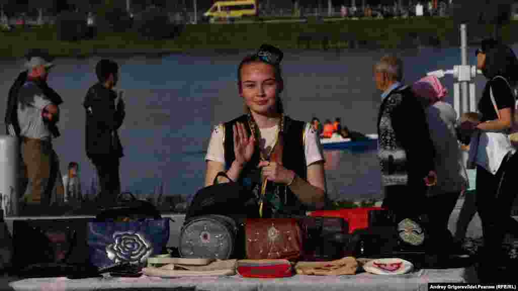 A girl sells handbags in traditional designs.