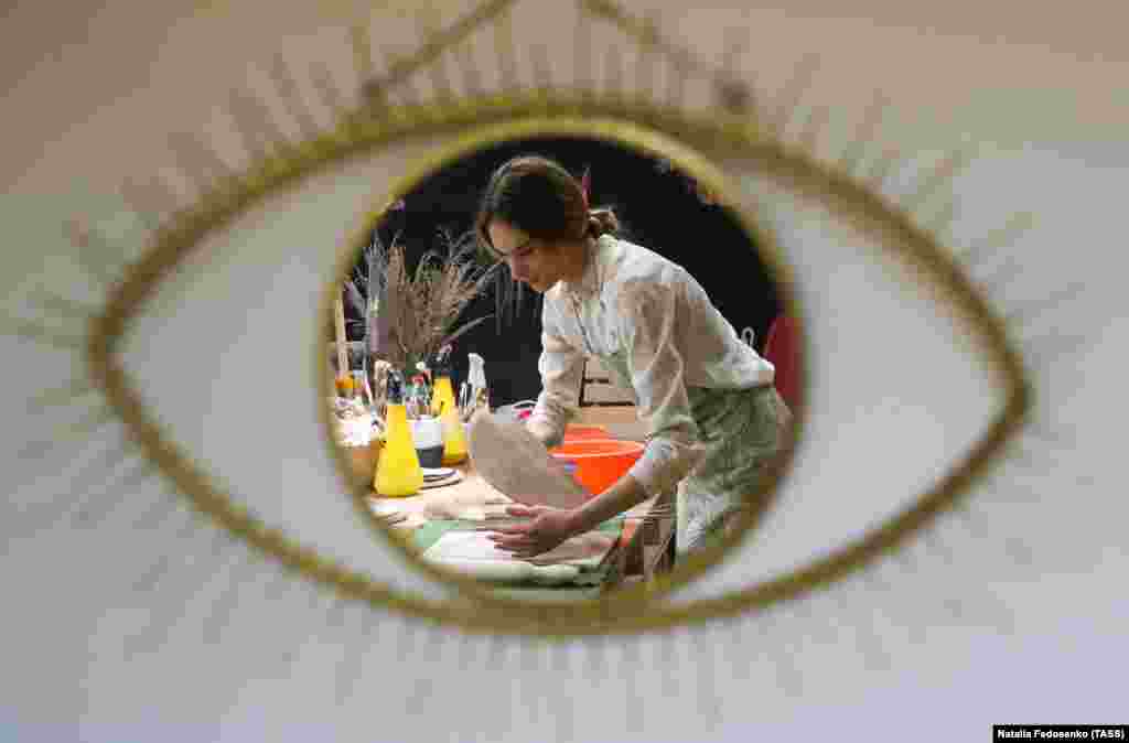 Yulia Yushina is seen through an eye-shaped opening in a piece of pottery in her Moon Ceramic pottery studio. The studio makes ceramic ware and ornamented pieces and offers pottery lessons. (TASS/Natalia Fedosenko)