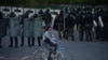 A protester rides her bike in front of Belarusian police officers during a rally to protest against the presidential inauguration in Minsk. (epa-EFE/STR)